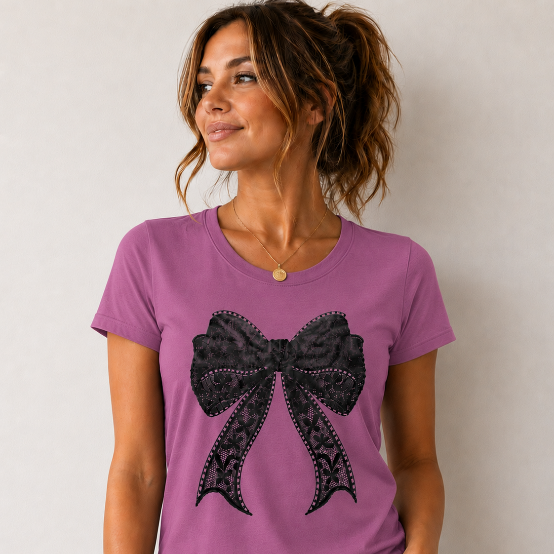 Woman wearing a purple t-shirt with a black bow design on a plain background