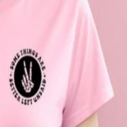 A person wearing a pink crew neck t-shirt with a graphic and text on the front.