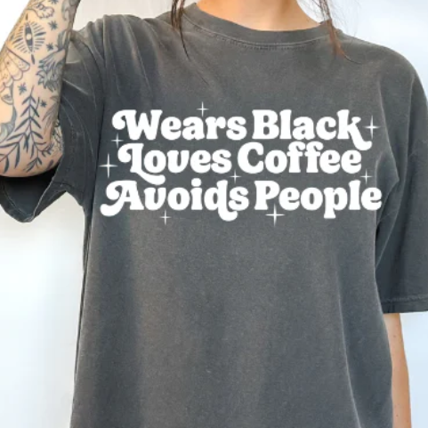 “Wears Black, Loves Coffee, Avoids People” sarcastic text graphic printed on a t-shirt.