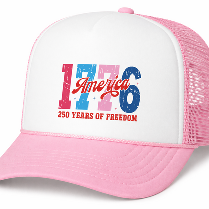 Pink and white trucker hat with '1776 America 250 Years of Freedom' text on a white background