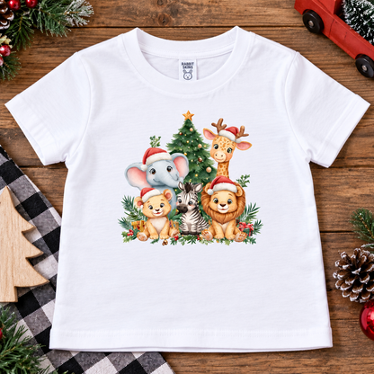 A white short-sleeve kids' t-shirt with a colorful Christmas animal graphic, laid flat on a rustic wooden background with holiday decorations.