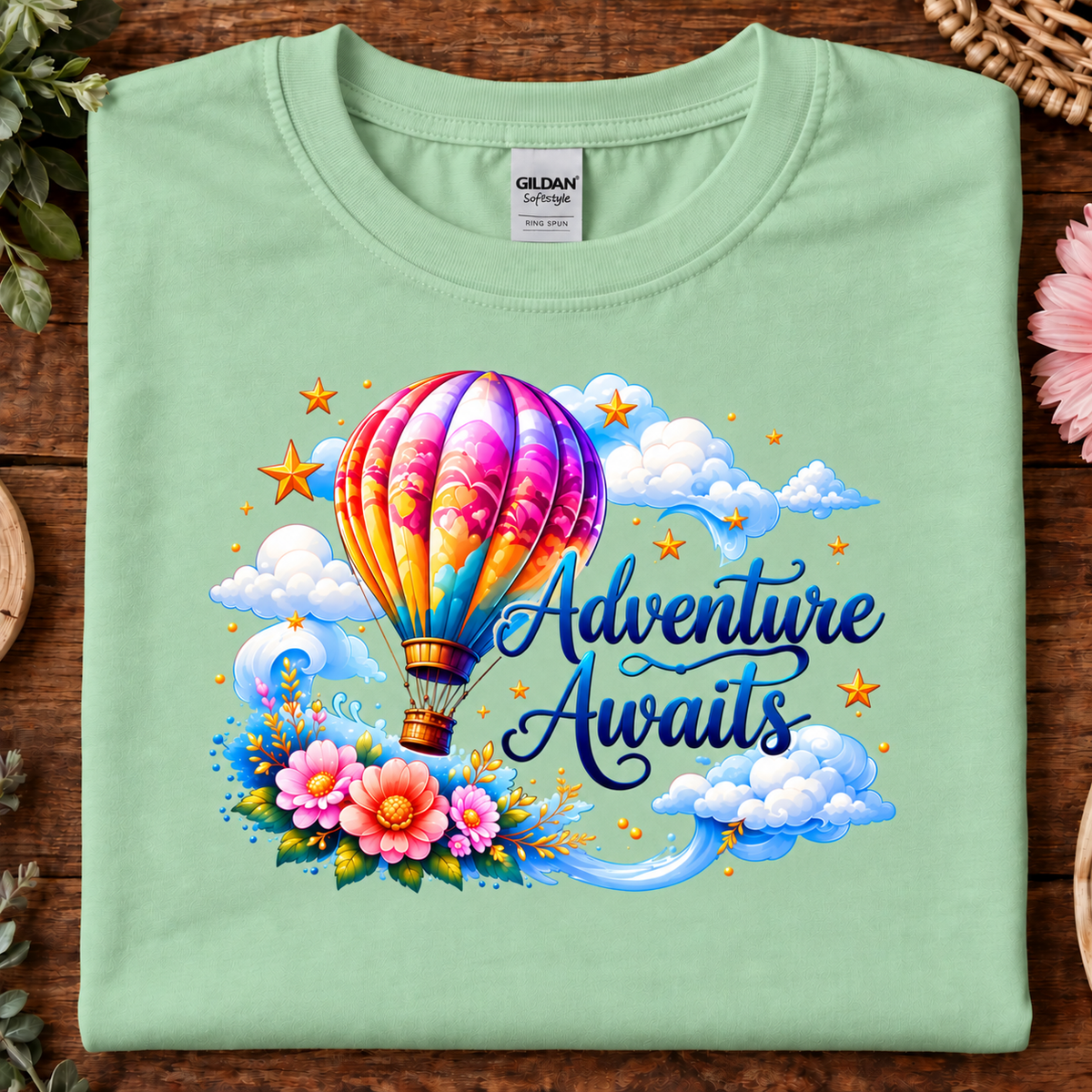 Mint green colored t-shirt with a hot air balloon flying in the clouds with the text Adventure Awaits