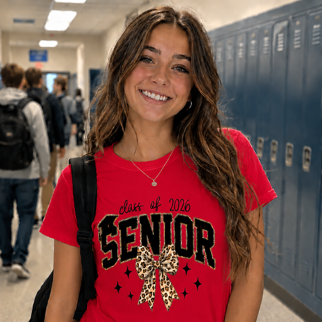 Young woman wearing a 'class of 2026 Senior' red t-shirt in a school hallway.
