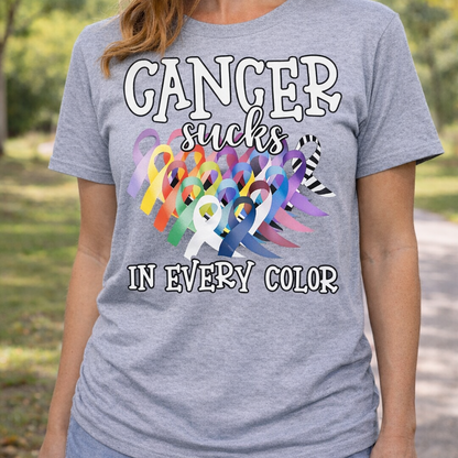 Person wearing a gray t-shirt with colorful cancer awareness ribbons and text outdoors.