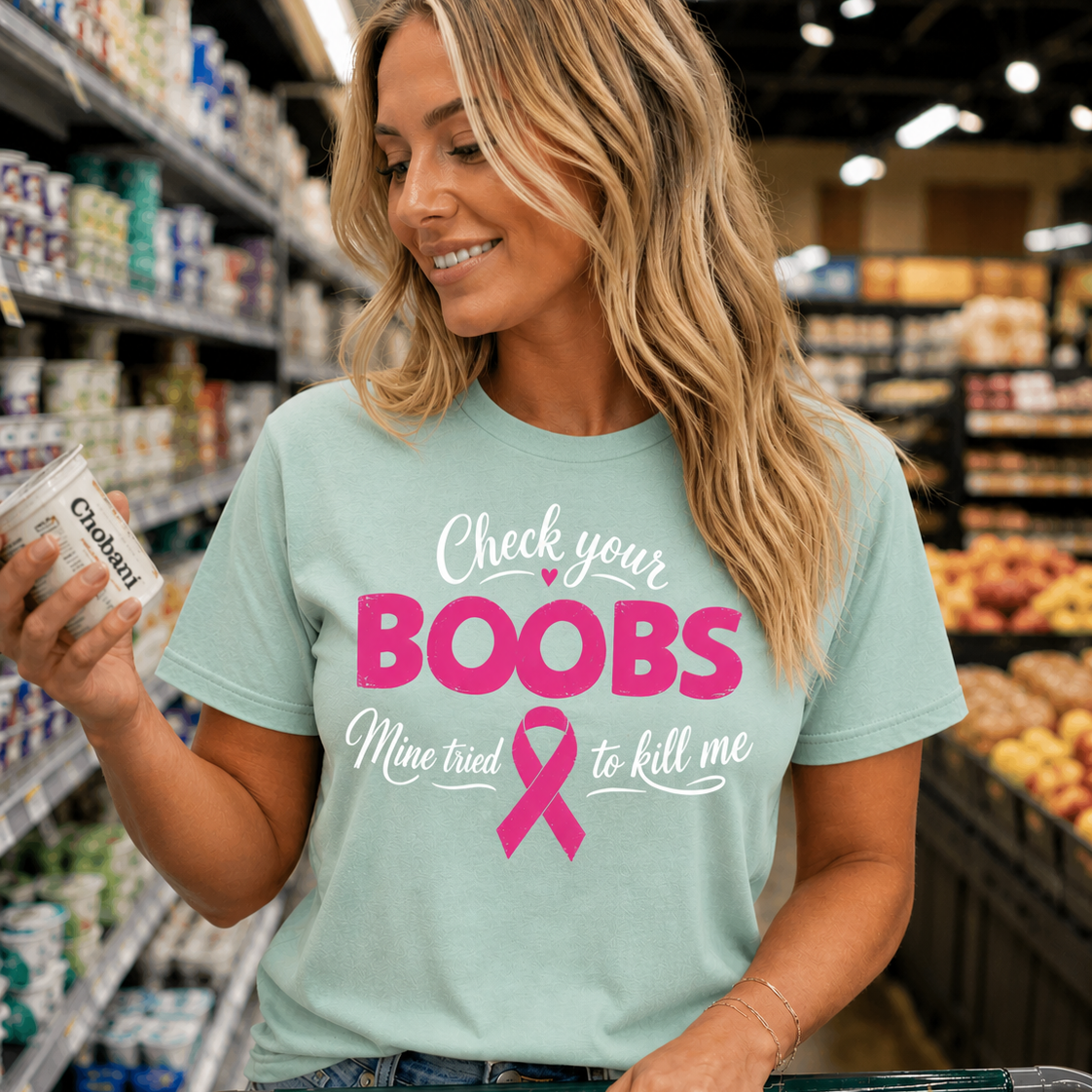Woman in a grocery store wearing a t-shirt with a humorous breast cancer awareness message.
