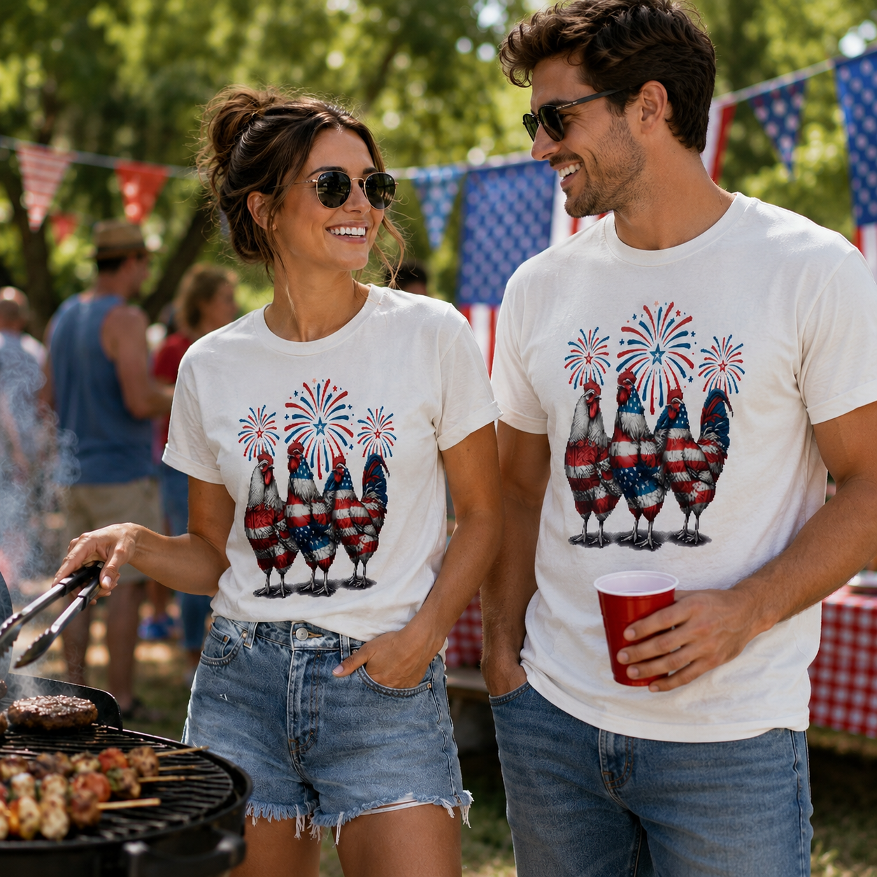Two people wearing matching white t-shirts with patriotic chicken designs at a barbecue event.