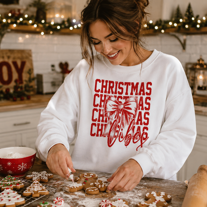 Woman in a kitchen wearing a 'Christmas Vibes' white sweatshirt decorating cookies.