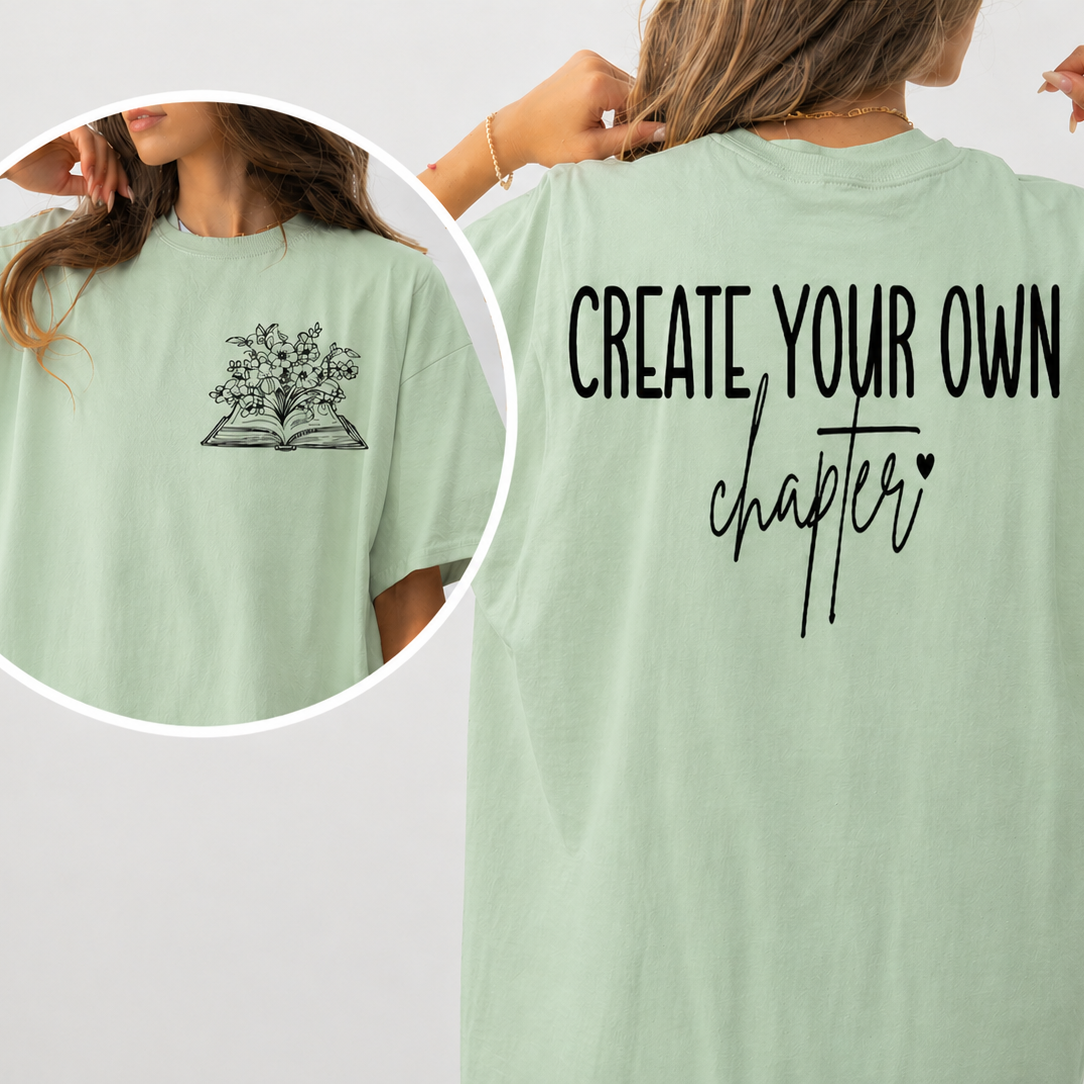 Light green t-shirt with 'Create Your Own Chapter' text and a small graphic on the back, worn by a person.