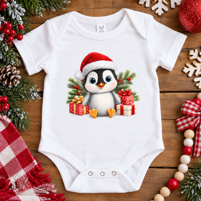 A white onesie with a penquin wearing a santa hat surrounded by presents 