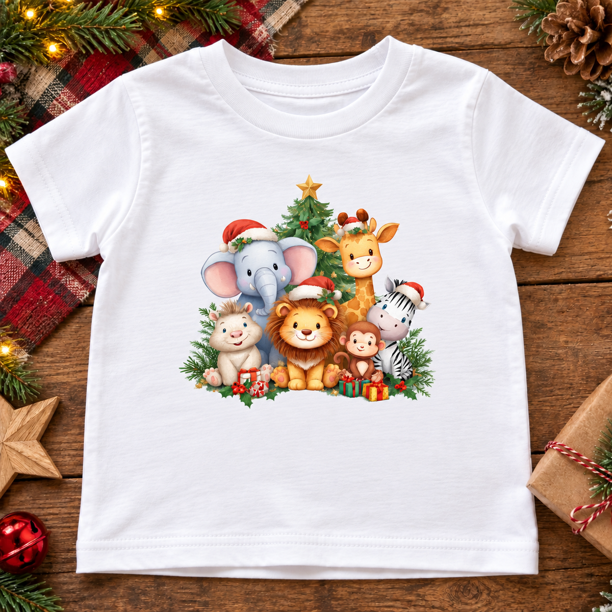 A white kids' short-sleeve t-shirt with a colorful Christmas cartoon animal graphic, displayed flat on a rustic wooden background with holiday decorations.