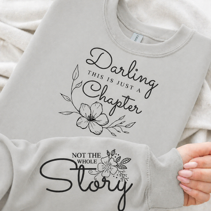 Ash gray sweatshirt with black floral text design held by a hand