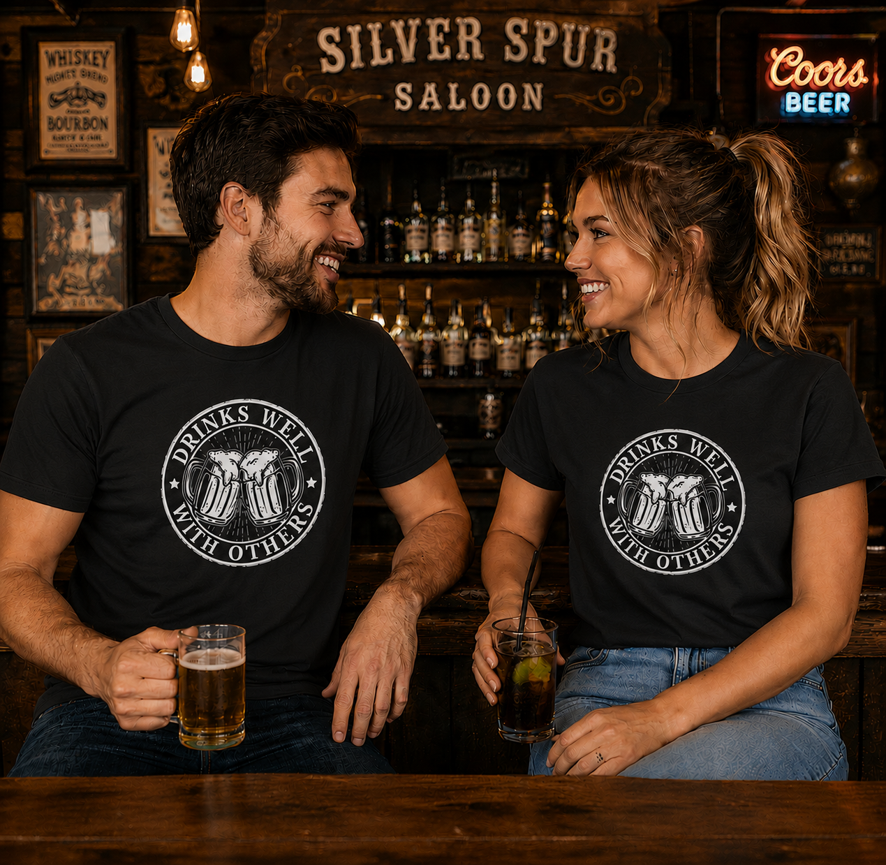 Two people sitting at a bar wearing matching black t-shirts with a beer-themed design, holding drinks.