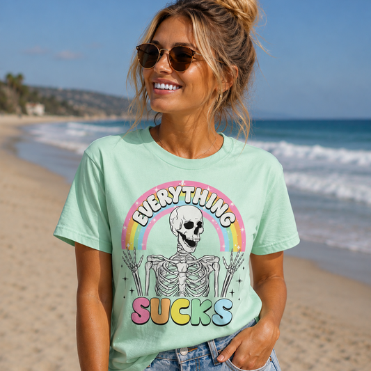 Woman wearing a Everything Sucks skeleton rainbow graphic t-shirt at the beach
