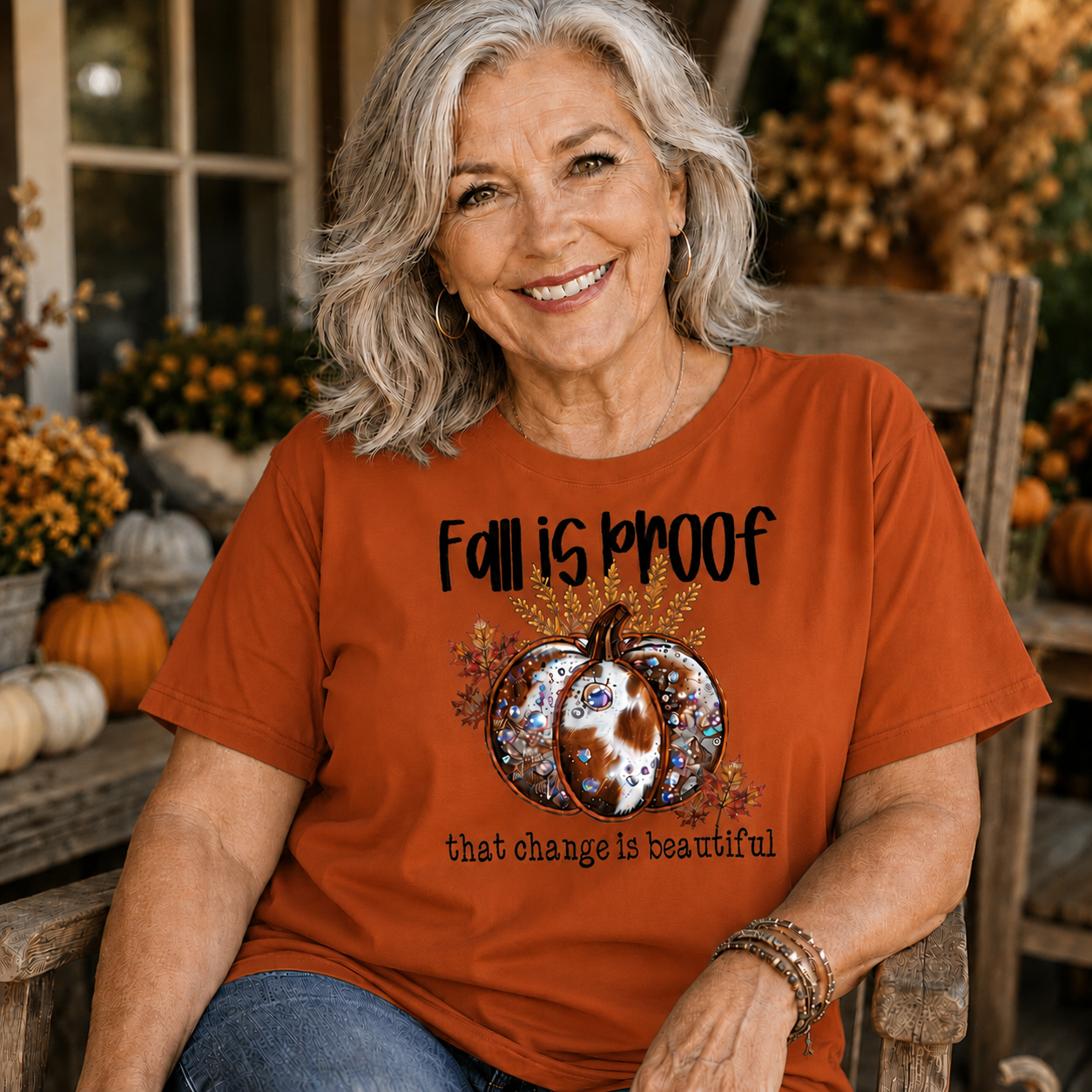 Woman wearing a yam colored t-shirt  with the phrase “Fall Is Proof That Change Is Beautiful” in faux-embroidery style.