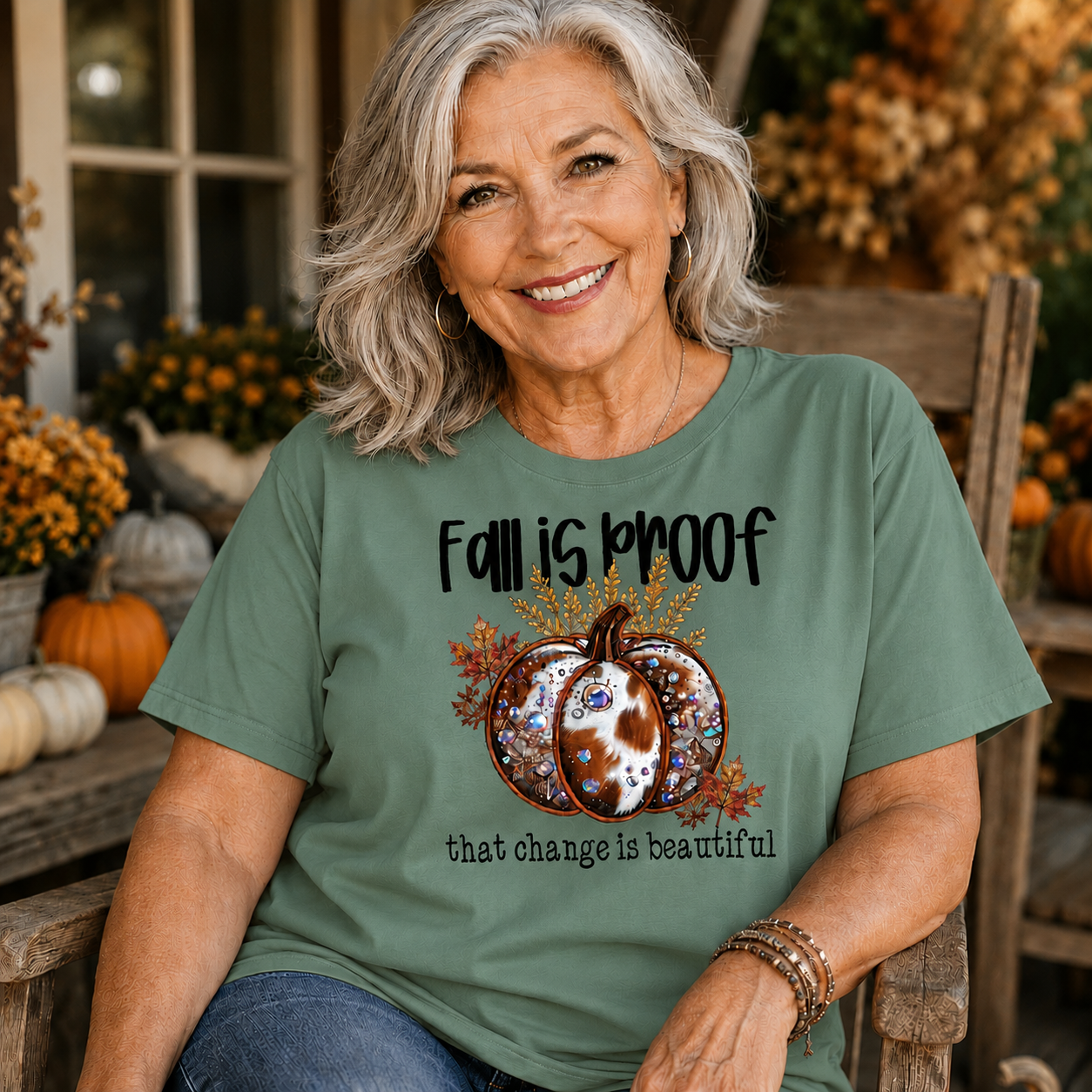 Woman wearing a light green colored t-shirt  with the phrase “Fall Is Proof That Change Is Beautiful” in faux-embroidery style.