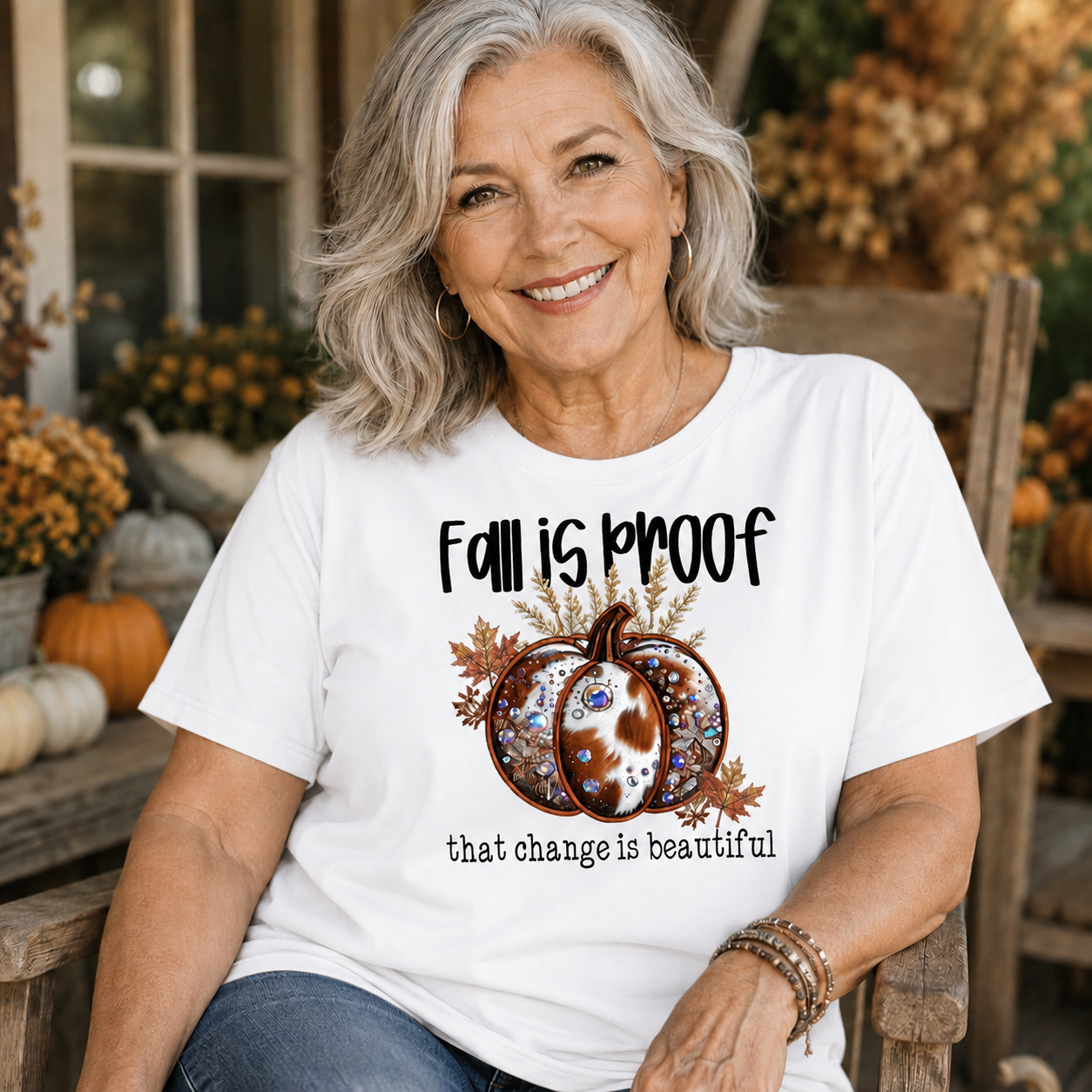 Woman wearing a white t-shirt  with the phrase “Fall Is Proof That Change Is Beautiful” in faux-embroidery style.