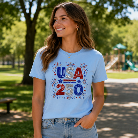 Woman wearing a sky blue t-shirt with 'USA 250' design in a park