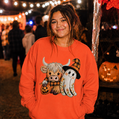 Person wearing an orange sweatshirt with a Halloween-themed design, standing in a festive outdoor setting.