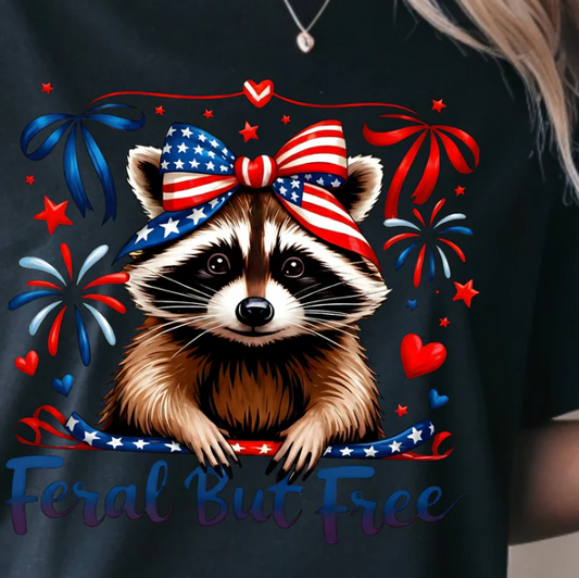 Red White and Blue Feral But Free raccoon design with patriotic bow, fireworks, and hearts for Fourth of July shirt