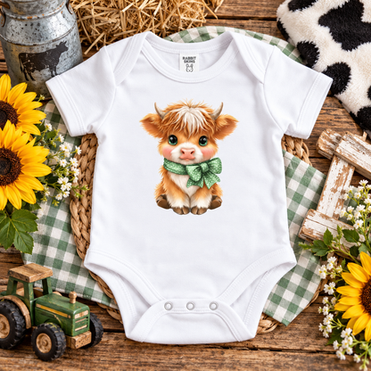 A white onesie with a highland cow graphic design with a bow