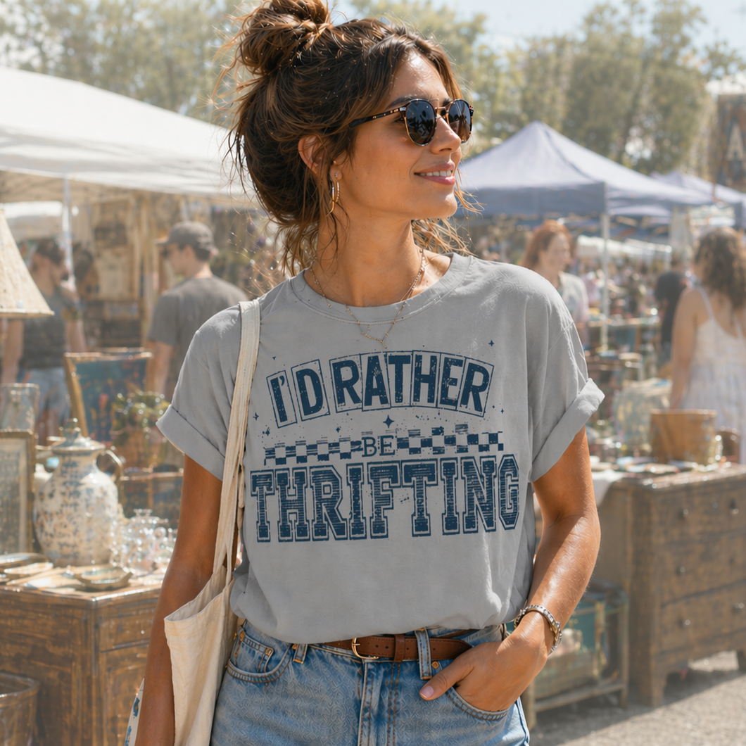 Woman wearing a t-shirt with 'I'd Rather Thrifting' at an outdoor market.