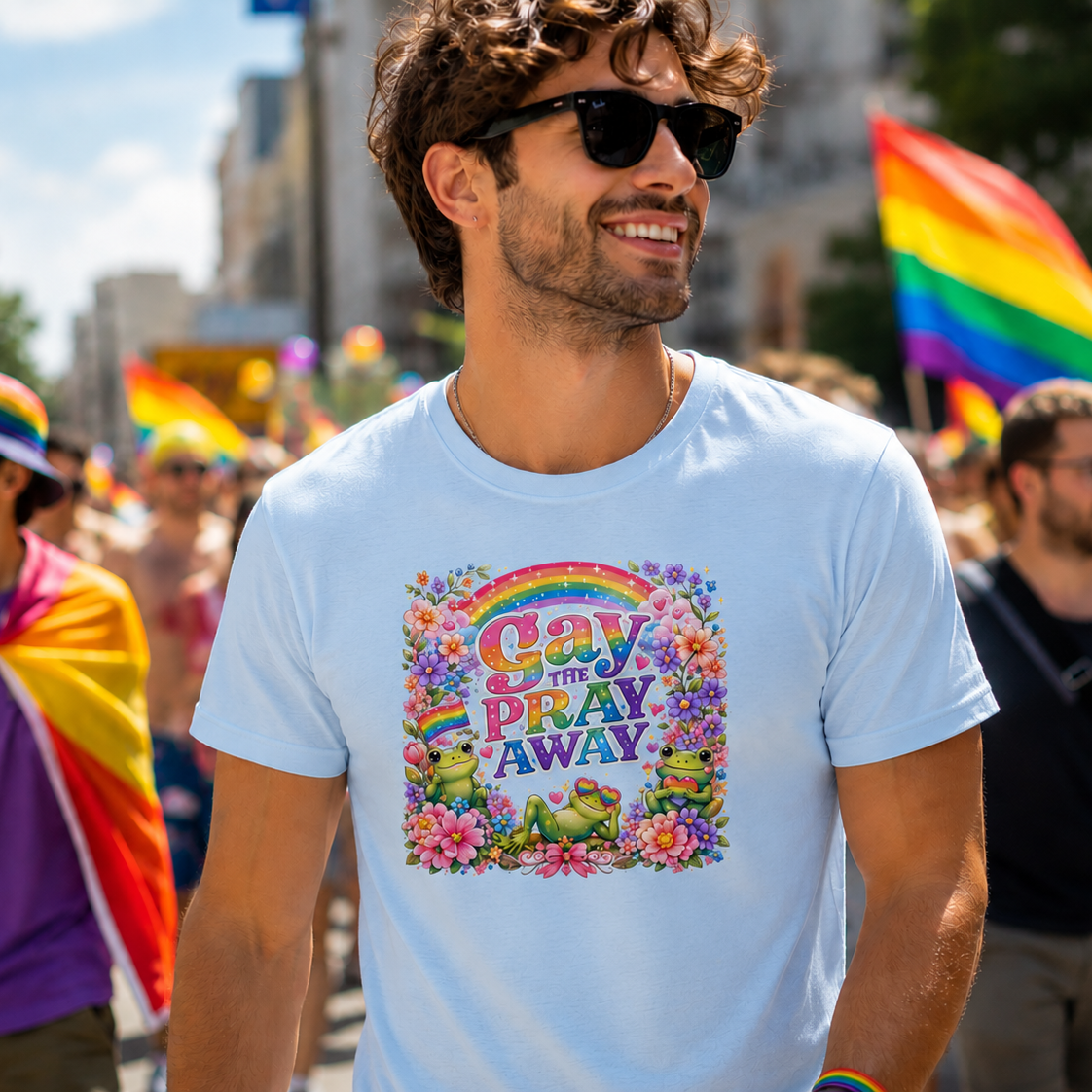 Man wearing a light blue Gay The Pray Away pride graphic t-shirt with rainbow frogs and flowers at a Pride parade.