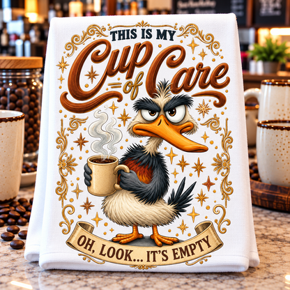 A white kitchen towel with a humorous coffee-themed graphic print, displayed on a granite countertop surrounded by coffee beans and mugs.