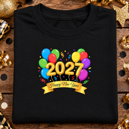 A folded black t-shirt features a colorful graphic of balloons and confetti with the year '2027' in gold balloon letters and a gold banner reading 'Happy New Year'.