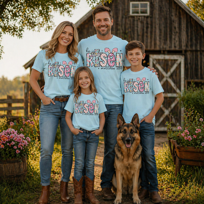 Family of four wearing a He is risen graphic t-shirt on chambray with a dog standing in front of a wooden barn.