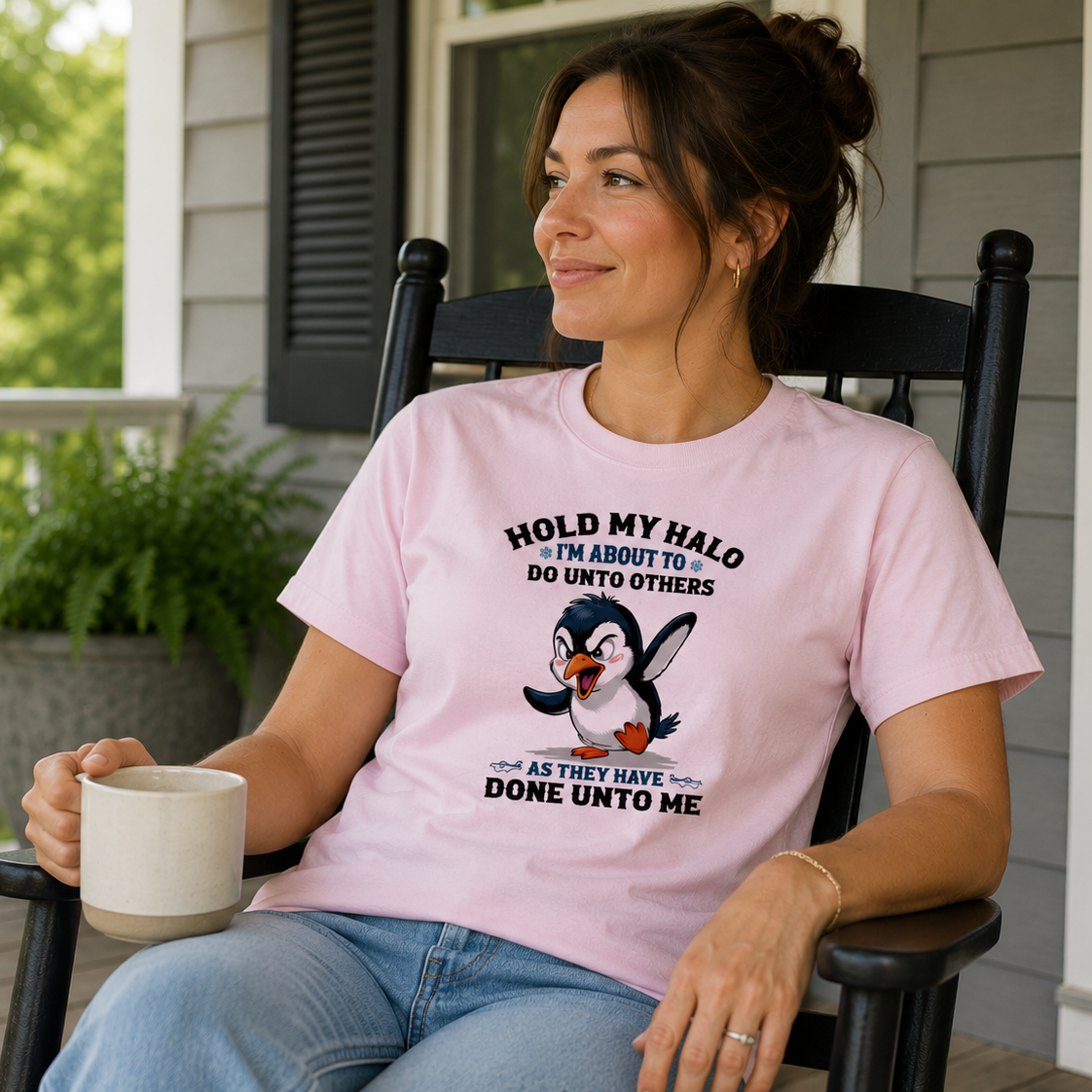 Woman sitting on a porch wearing a pink t-shirt with a penguin graphic and text.