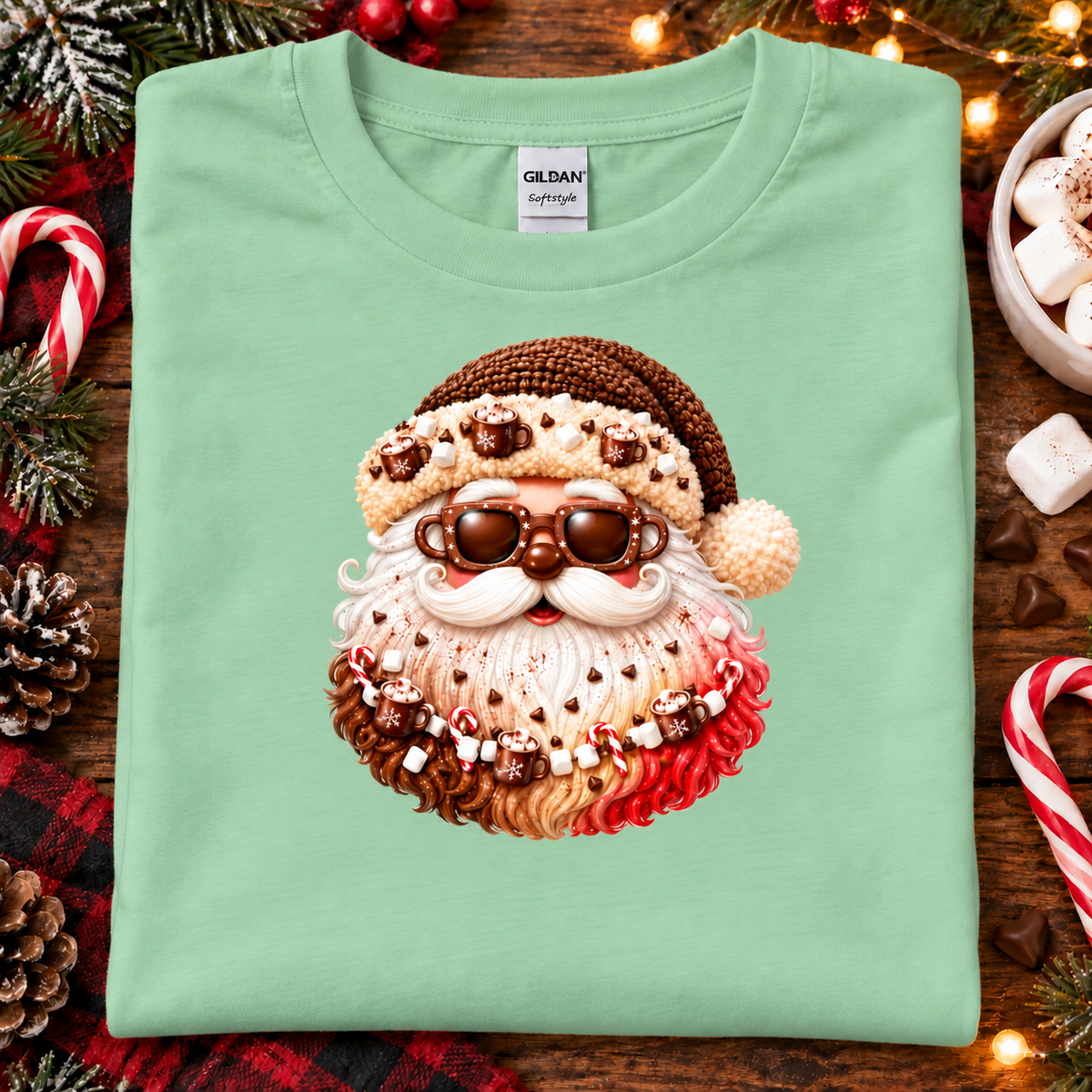 A folded mint green Gildan Signature T-shirt with a festive hot chocolate Santa graphic, styled on a rustic wooden background with Christmas decorations.