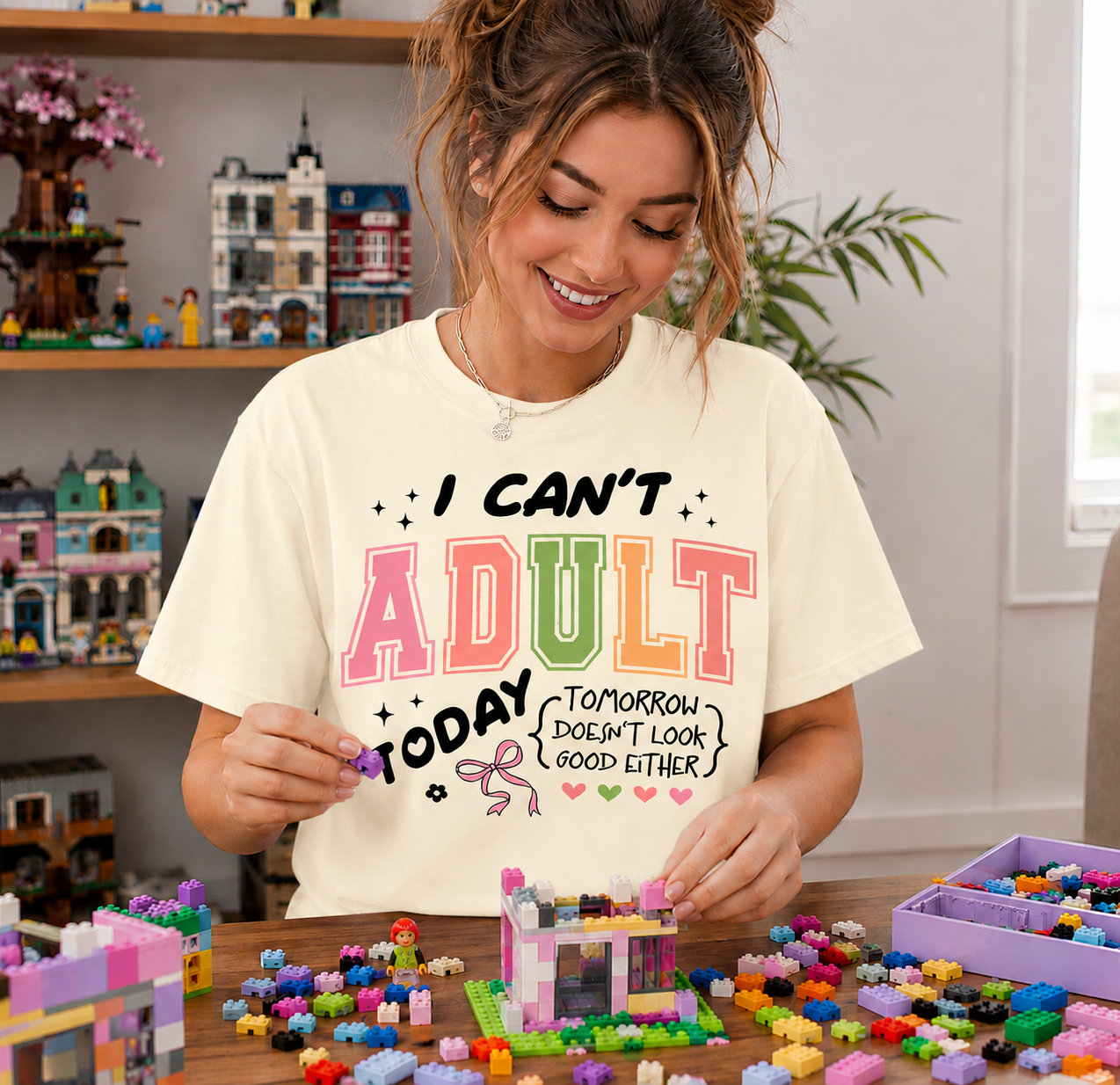 Woman wearing a white t-shirt with colorful text, playing with building blocks in a room filled with toys.