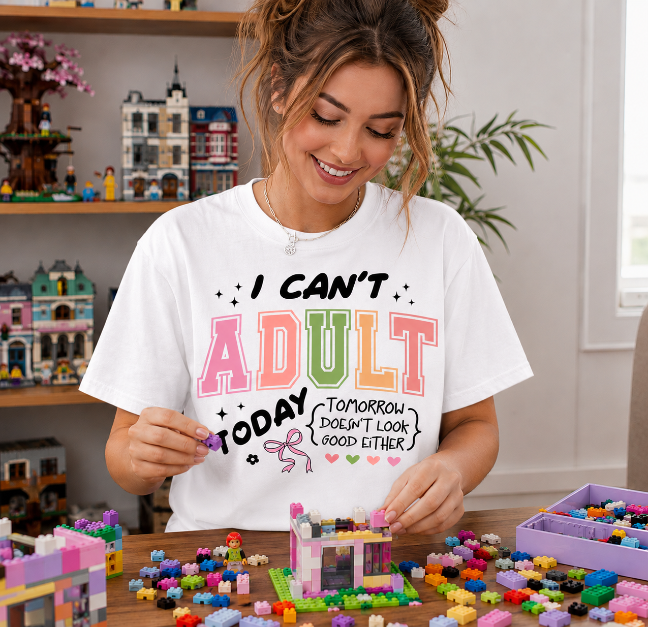 Woman wearing a white t-shirt with colorful text, sitting at a table with building blocks.
