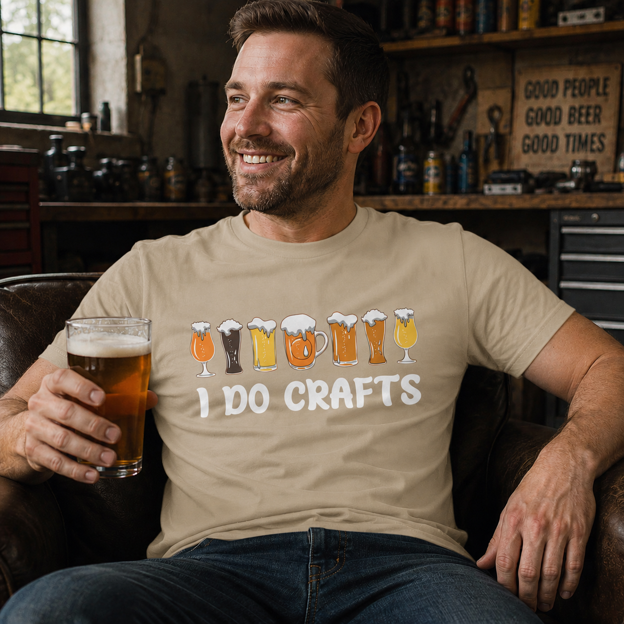 Man sitting in a chair holding a glass of beer, wearing a 'I Do Crafts' sand colored t-shirt.
