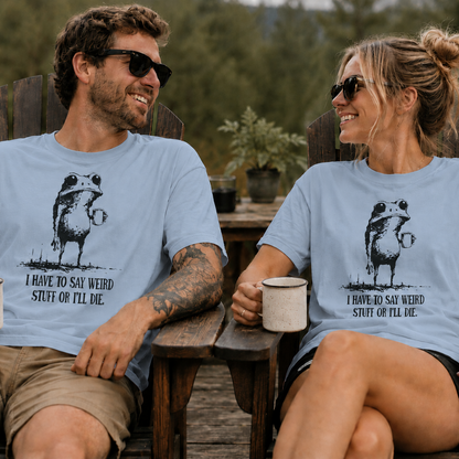 Two people sitting outdoors wearing matching light blue t-shirts with a graphic of a frog with humorous text