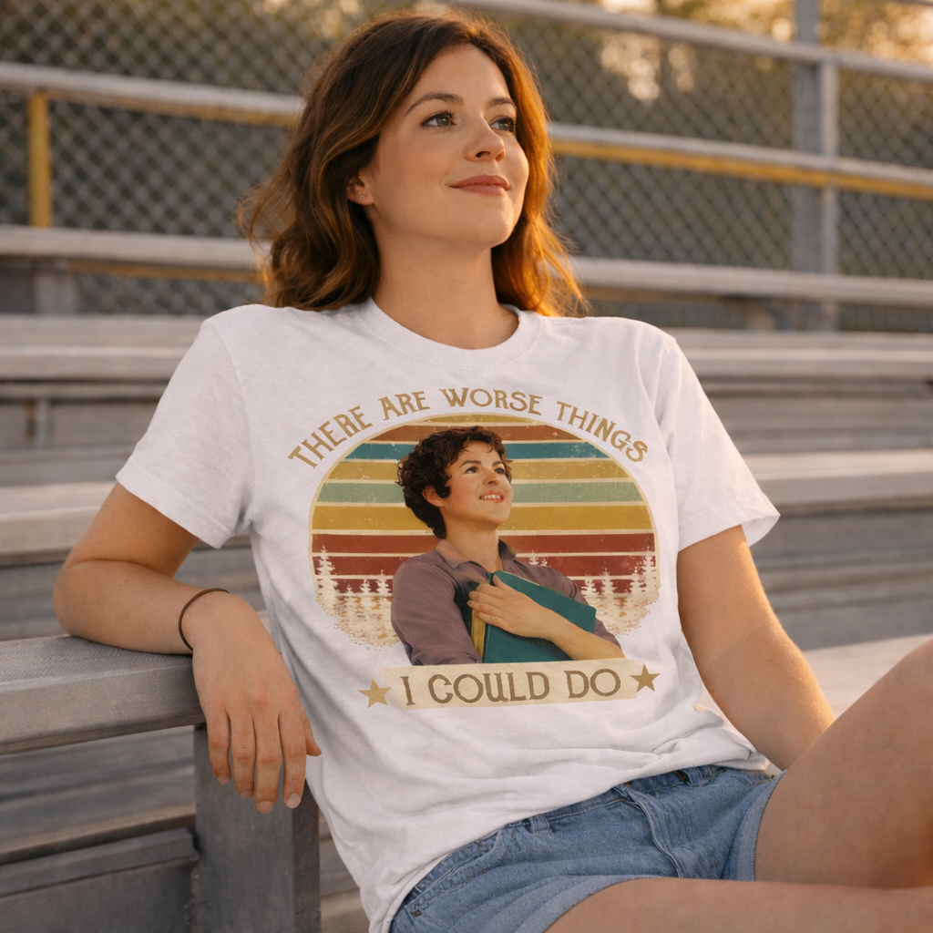 Woman wearing a t-shirt with a graphic design sitting on bleachers.