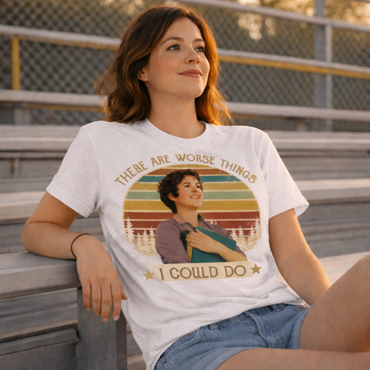 Woman wearing a t-shirt with a graphic design sitting on bleachers.