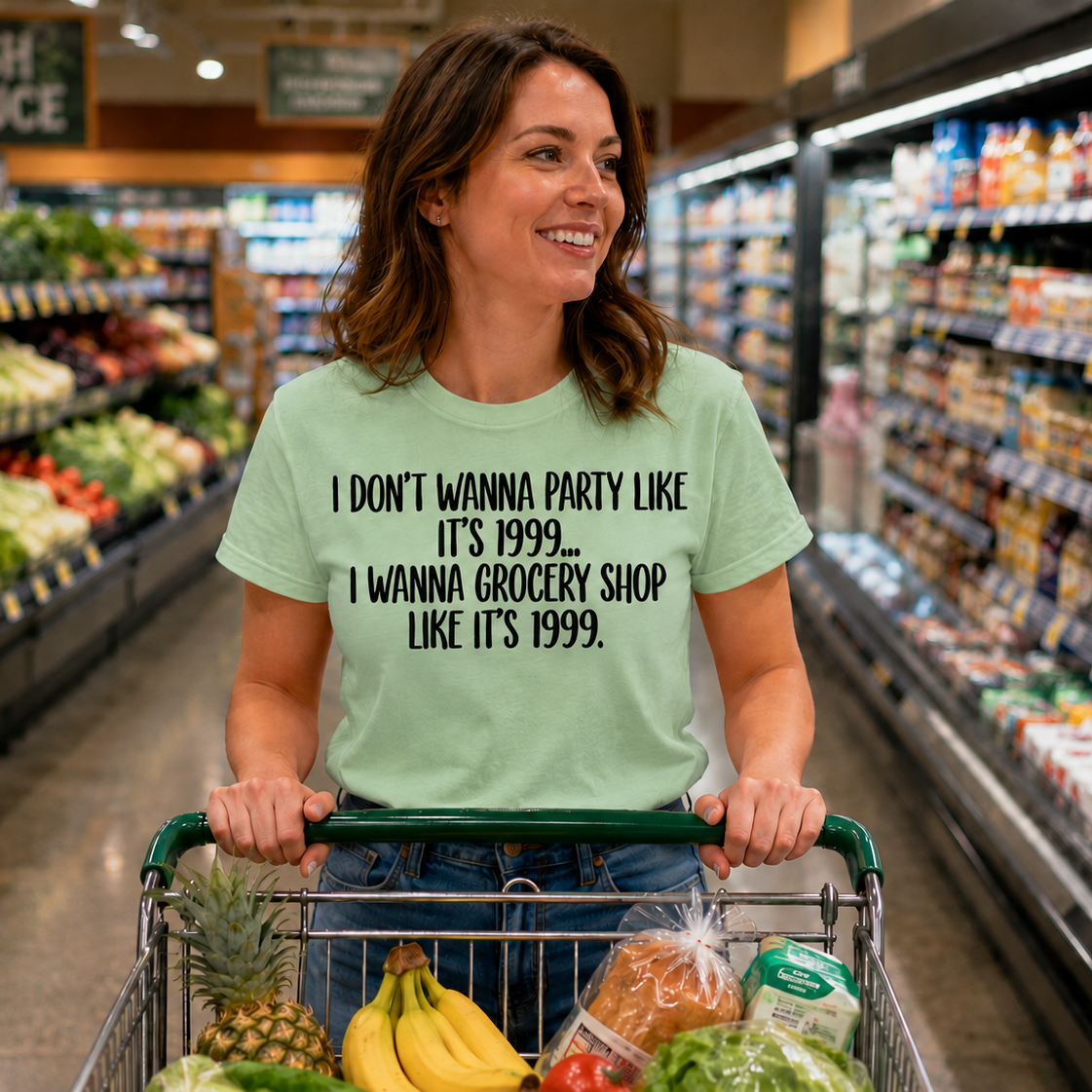 Woman in a grocery store pushing a cart with produce, wearing a t-shirt with a humorous text.