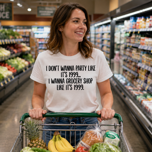 Woman in a grocery store pushing a cart with a humorous t-shirt, surrounded by produce and shelves.