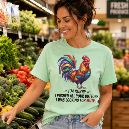 A woman in a grocery store aisle wearing a mint green graphic t-shirt with a colorful rooster and the text 'I'M SORRY I PUSHED ALL YOUR BUTTONS. I WAS LOOKING FOR MUTE.