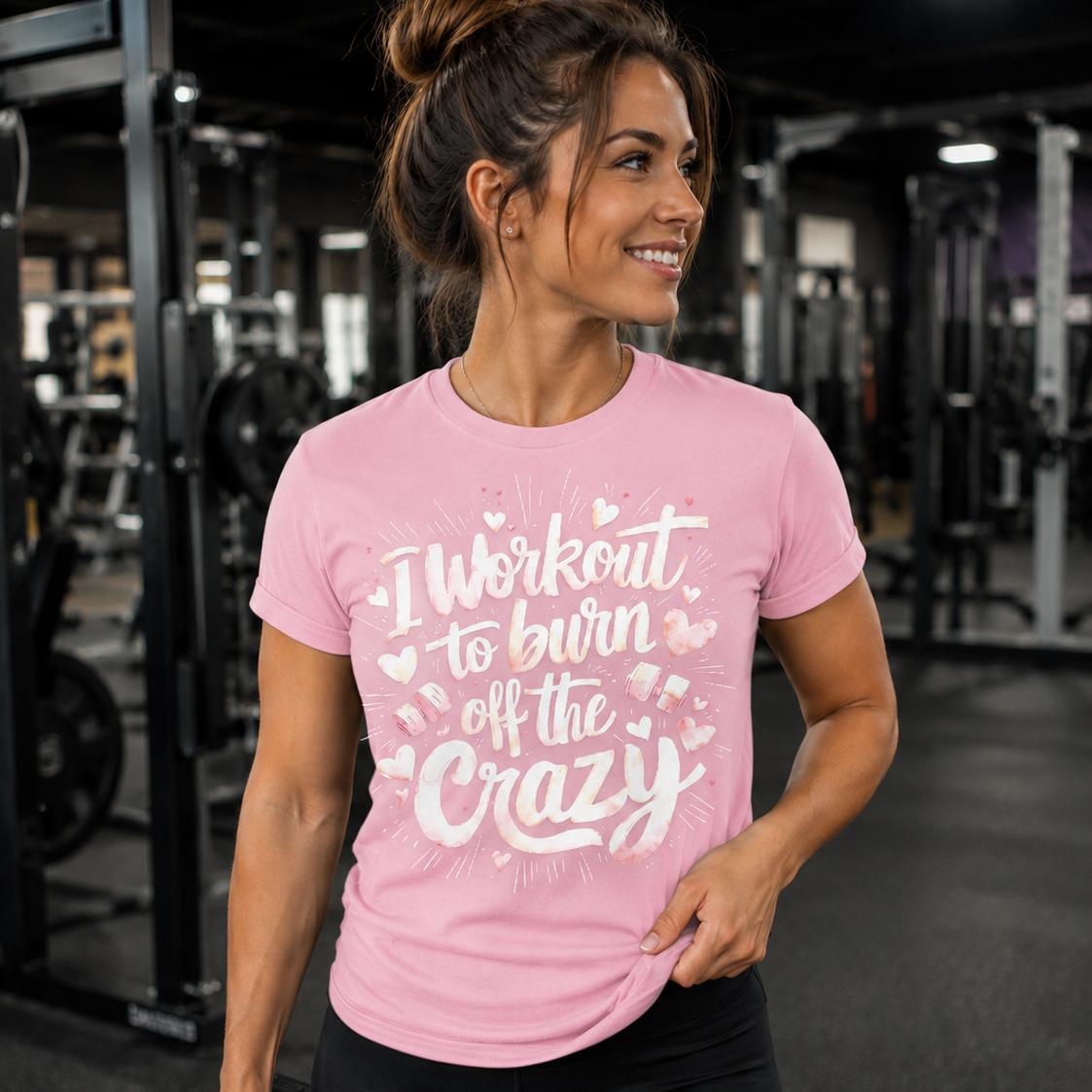 Woman in a gym wearing a blossom t-shirt with text, holding a dumbbell.
