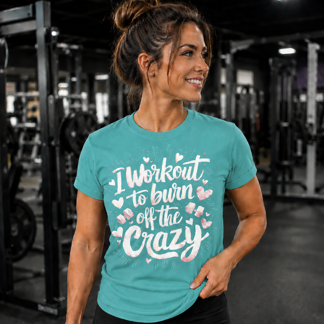 Woman in a gym wearing a chalky mint t-shirt with text and holding a dumbbell.