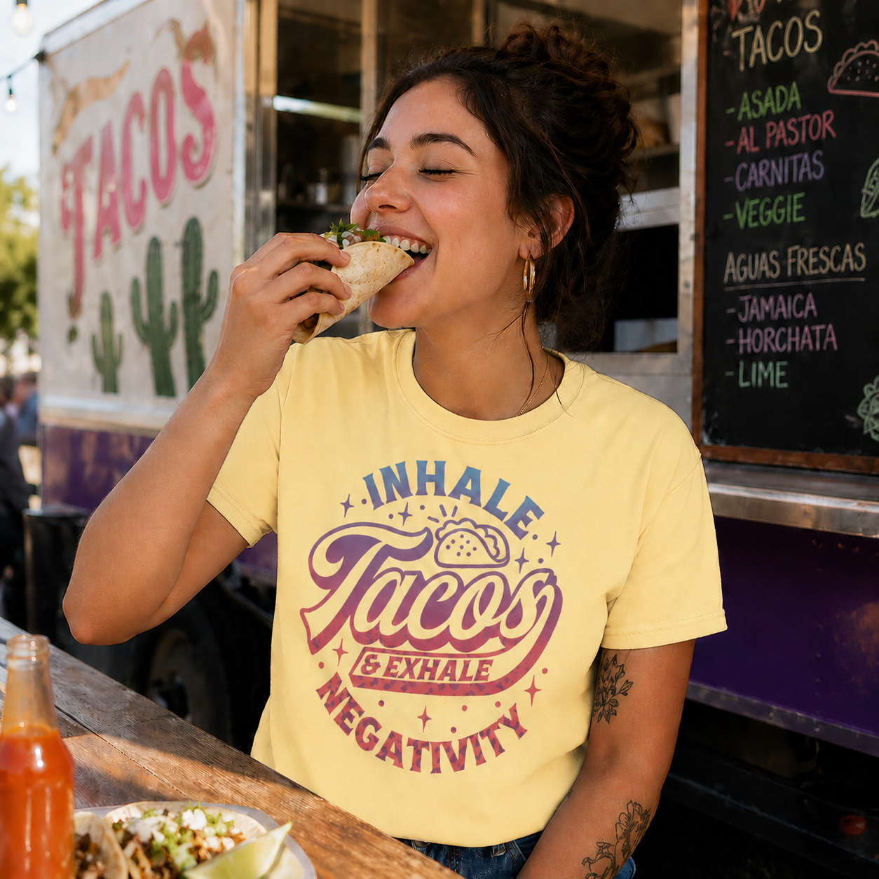 Woman wearing an butter colored t-shirt with a graphic design with text Inhale Tacos Exhale Negativity