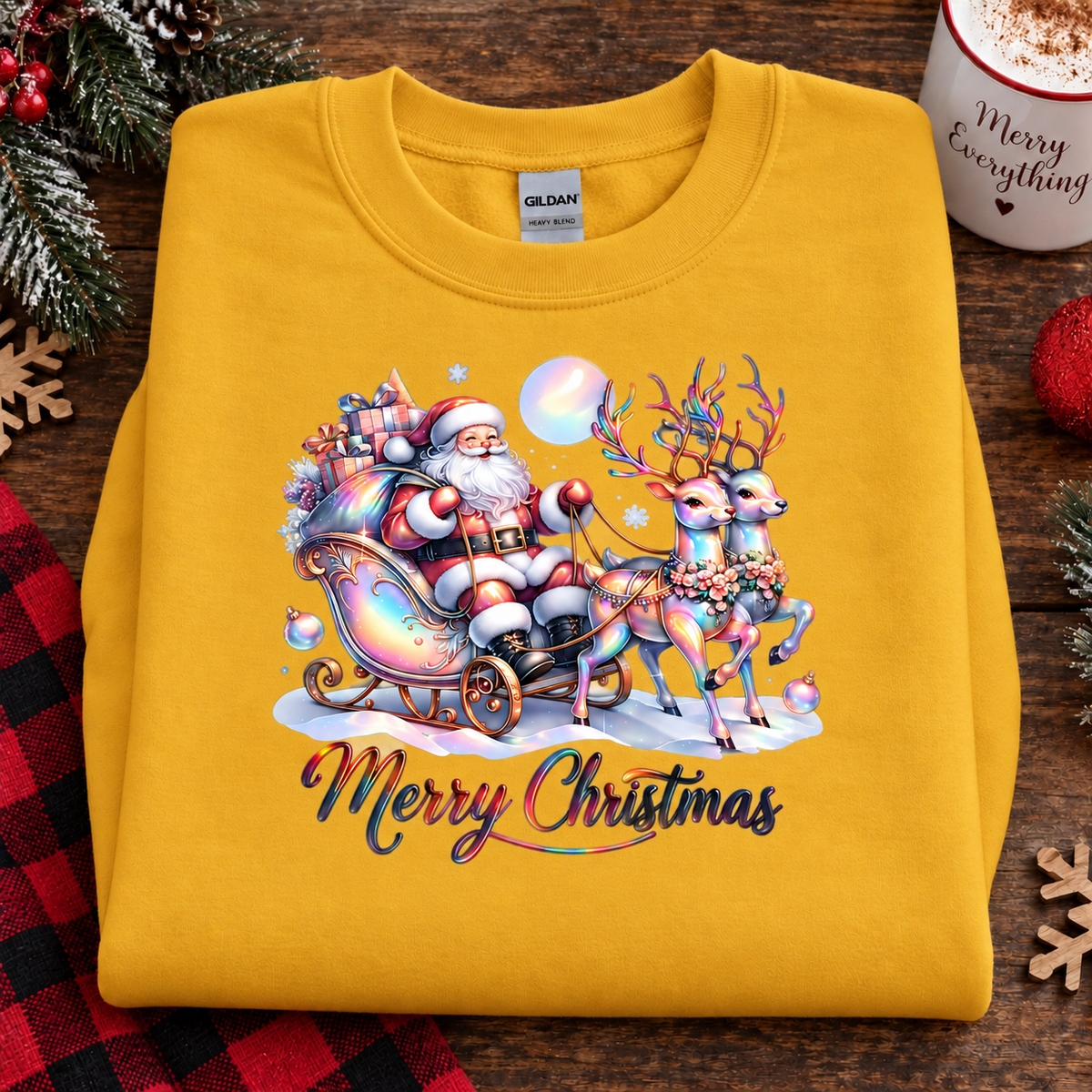 A folded yellow Gildan sweatshirt with a colorful Christmas graphic of Santa Claus in a sleigh with reindeer, displayed on a rustic wooden table with holiday decorations.