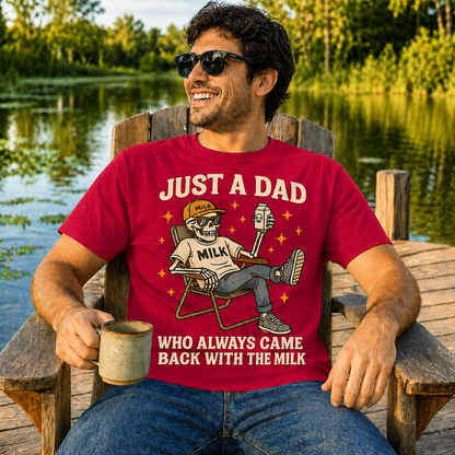 Man wearing a heather red colored t-shirt with a graphic and text, sitting by a lake.