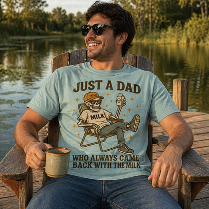 Man wearing a light blue colored t-shirt with a graphic and text, sitting by a lake.