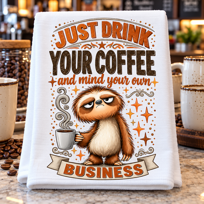 A white kitchen towel with a humorous sloth graphic and the text 'JUST DRINK YOUR COFFEE and mind your own BUSINESS' 