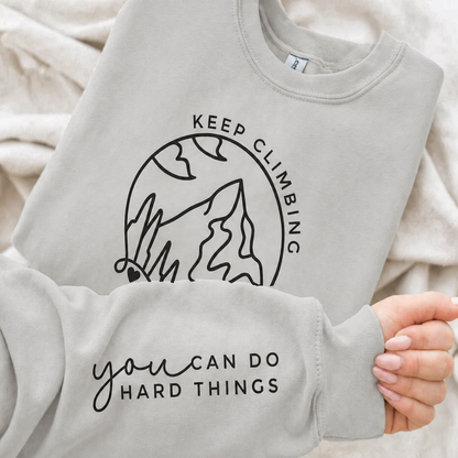 Ash gray sweatshirt with motivational text and mountain graphic .