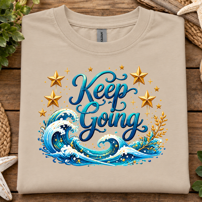 Sand colored t-shirt with a ocean and stars graphic with text Keep Going