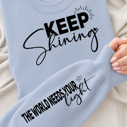 Light blue sweatshirt with the inspirational saying "Keep Shining the World Needs Your Light".
